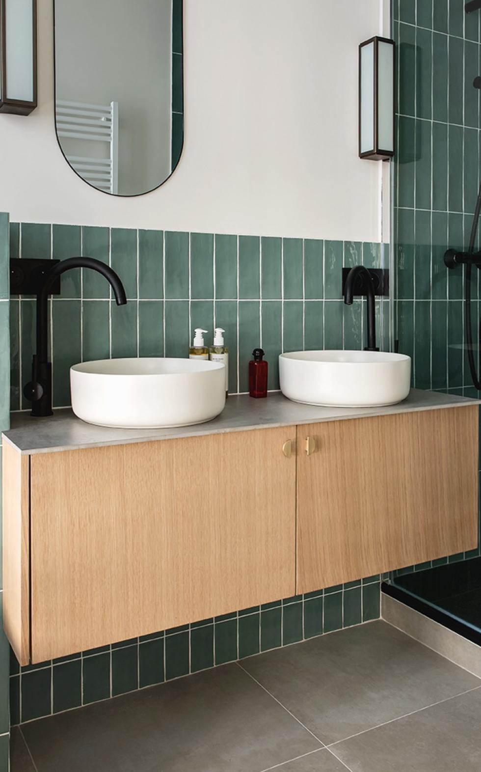 Suspended bathroom cabinet in natural oak, with green ceramic tiles.